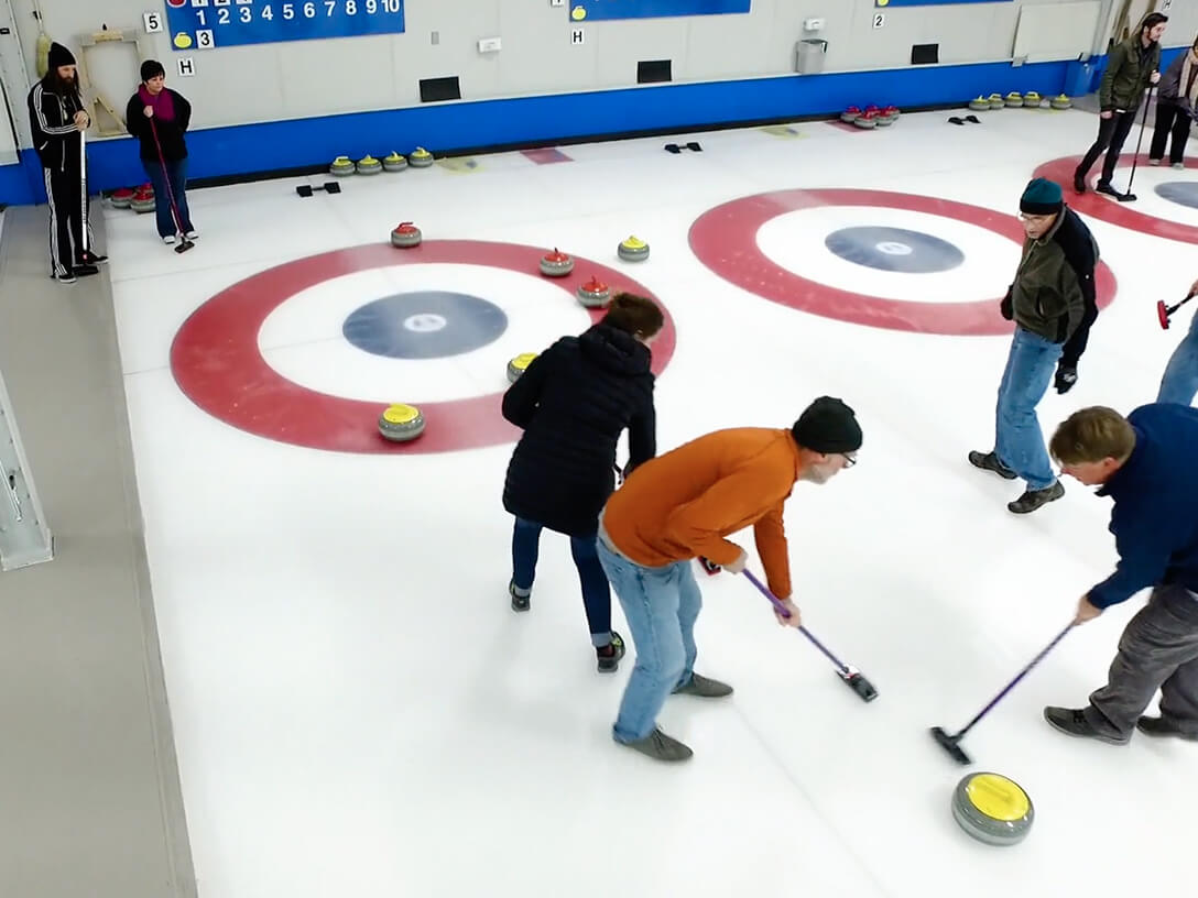 Media Loft employees playing the sport Curling on an ice rink