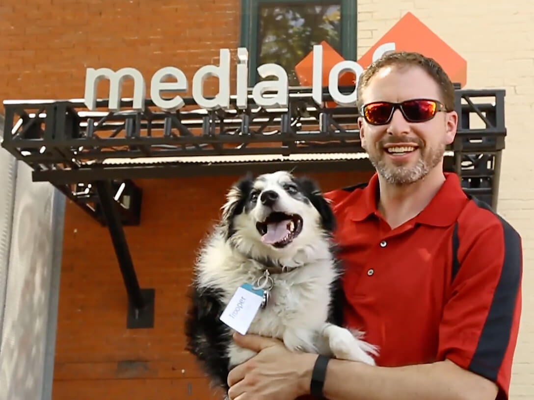 Man posing with dog in front of Media Loft office